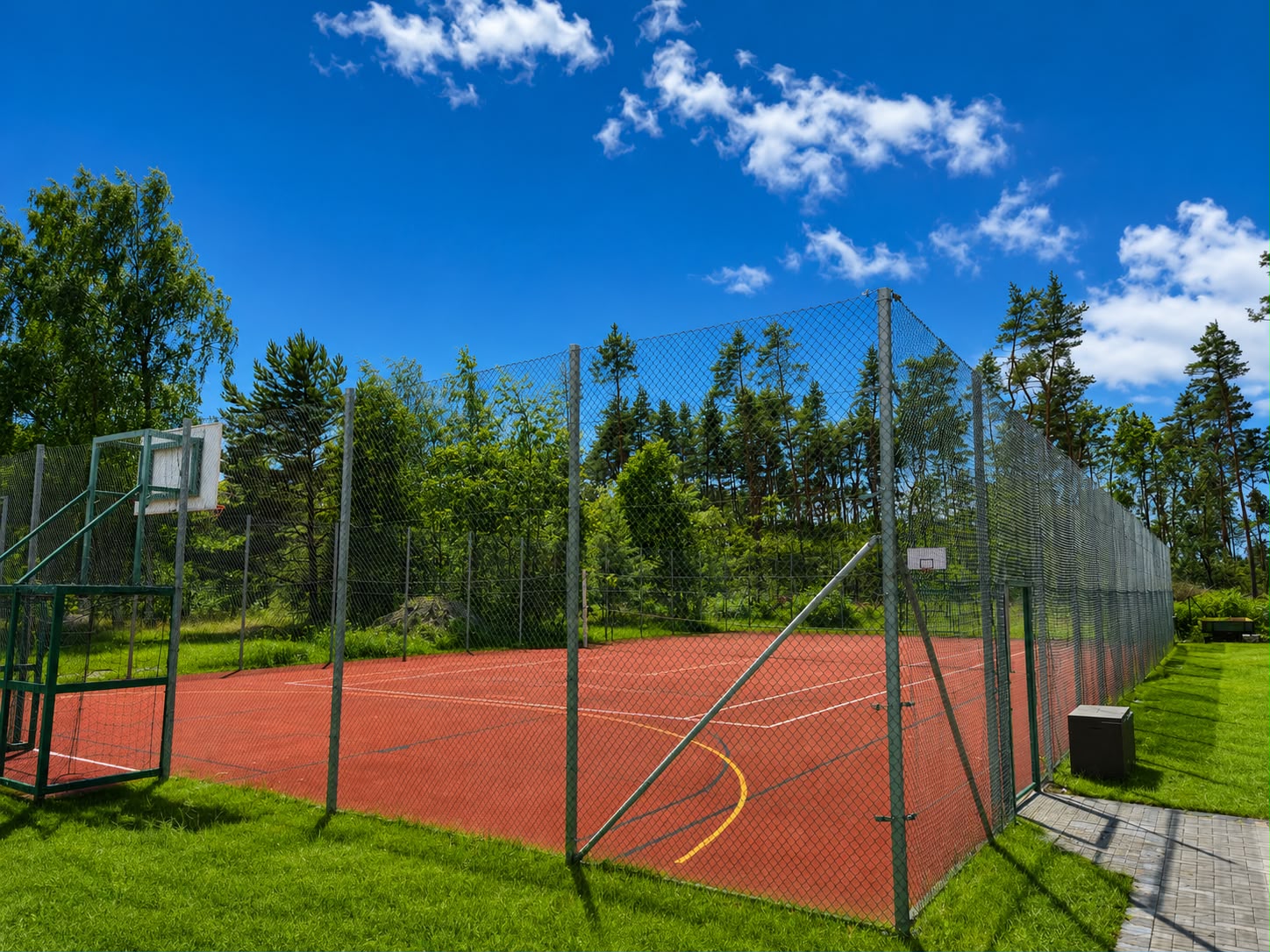 Multifunktionsplatz mit Tartanbelag, Basketballkörben und Ballfangzaun